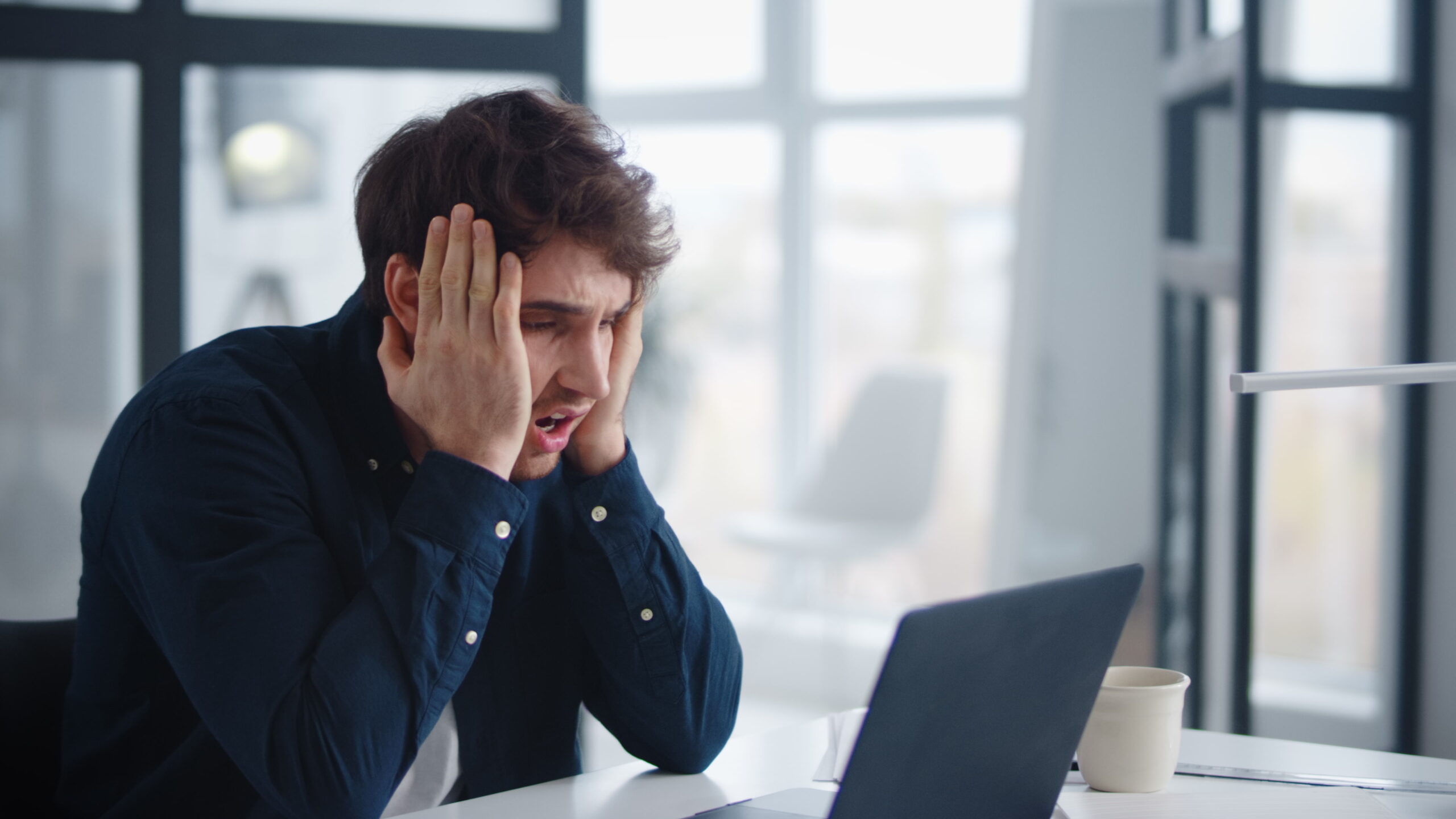 homme anxieux se tenant la tête devant ordinateur - soledis agence e-commerce